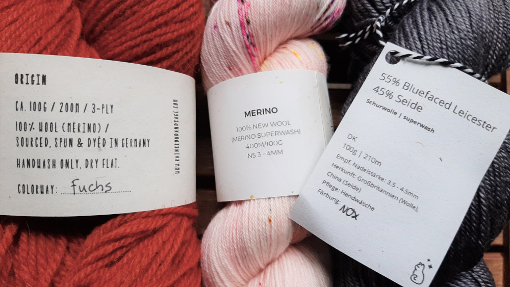 Some yarn labels with information about the fiber type, yardage and weight.
